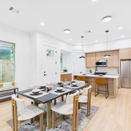 Open-concept living and dining area with large kitchen island, designer finishes, and natural light in Houston new construction home.