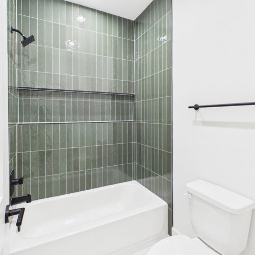 Designer green tile and sleek black fixtures create a sophisticated secondary bath.