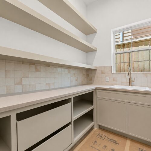 Walk-in pantry in luxury home in The Heights Houston featuring custom shelving, countertop workspace, and additional storage.