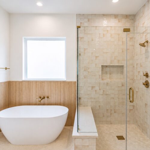 Luxury primary bathroom in The Heights Houston featuring a freestanding soaking tub, walk-in glass shower, custom tile, and designer brass fixtures.