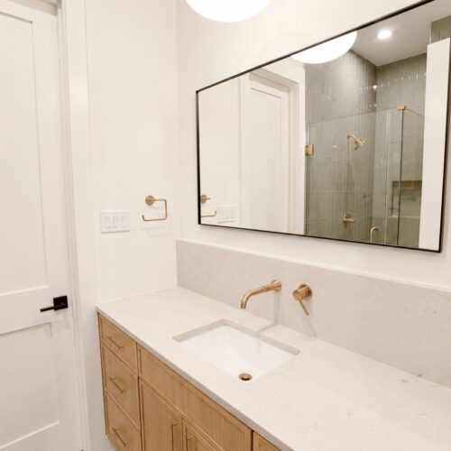 Luxury first-floor guest bathroom in The Heights Houston home featuring a frameless glass shower, wood vanity, and modern finishes.