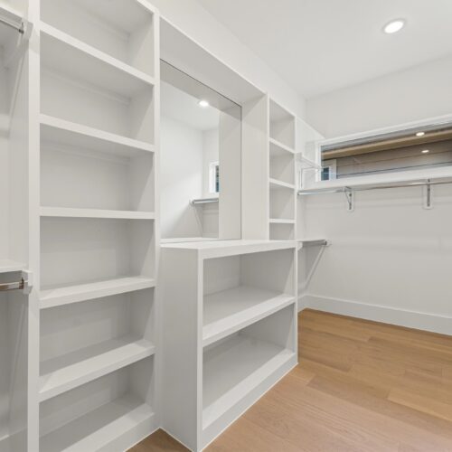 Luxury primary walk-in closet in The Heights Houston featuring custom built-in shelving, dressing area, and extensive storage space.