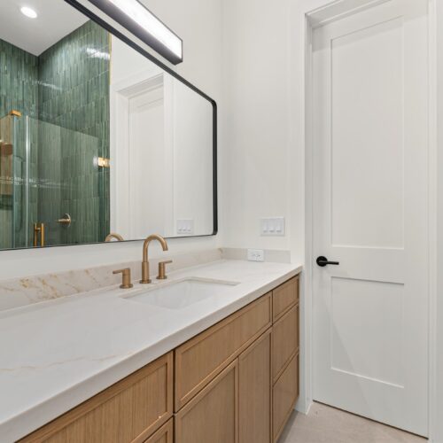 Secondary bathroom in luxury home in The Heights Houston featuring a custom green tile shower, quartz vanity, and designer finishes.